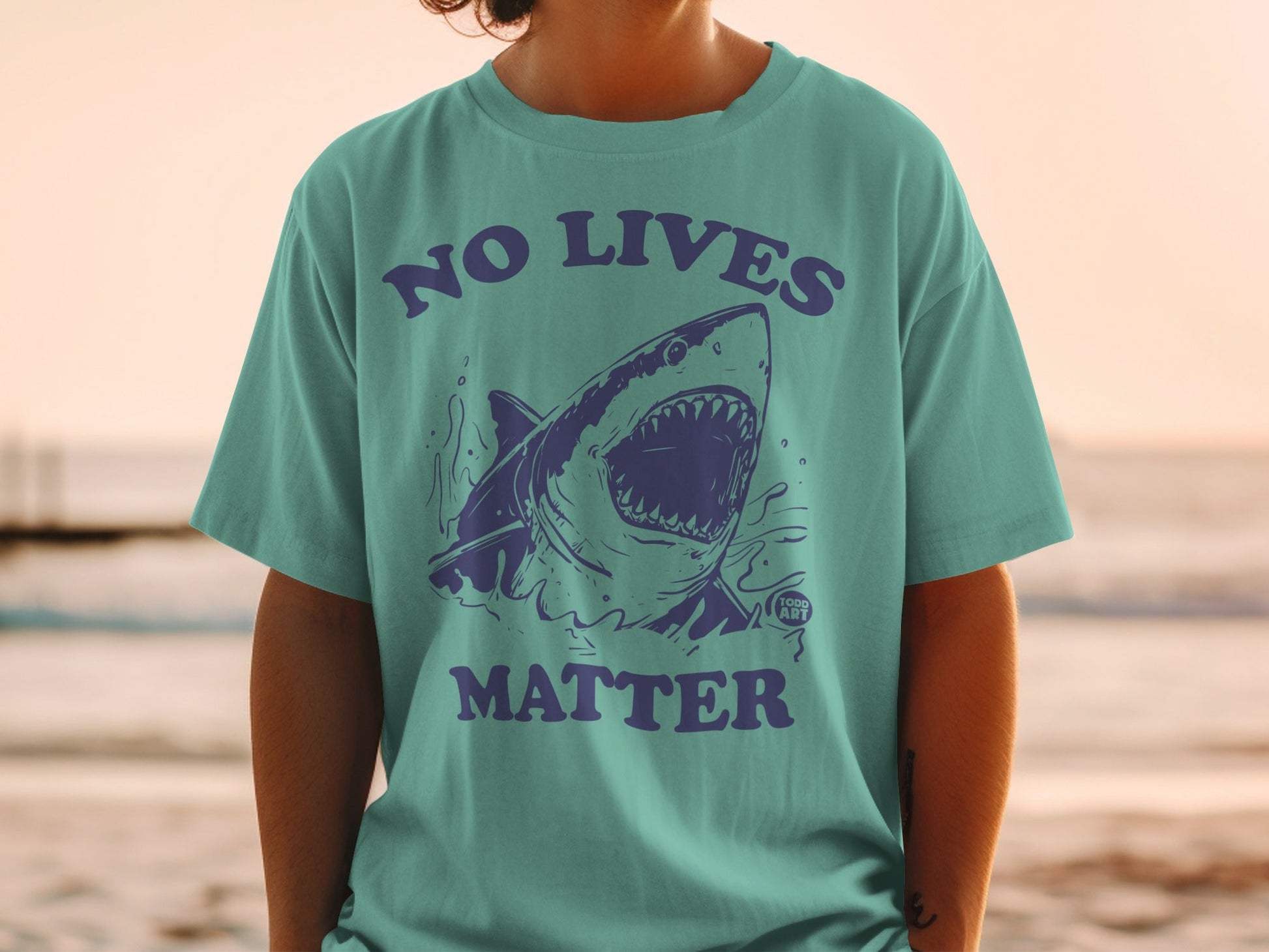 Teal t-shirt with a graphic of a shark and text reading "NO LIVES MATTER".