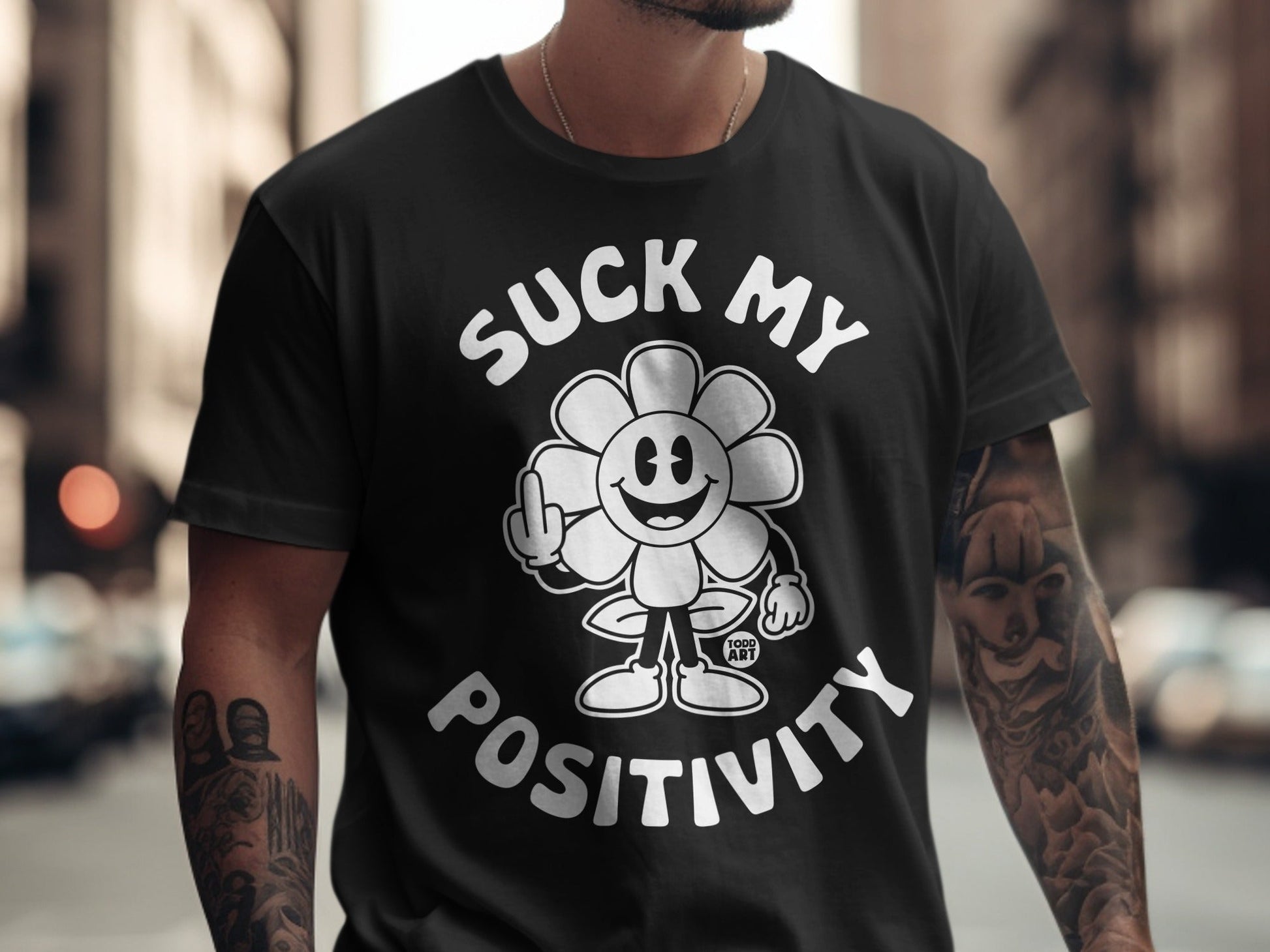 Black t-shirt with a cartoon flower giving the middle finger, text says "Suck My Positivity".
