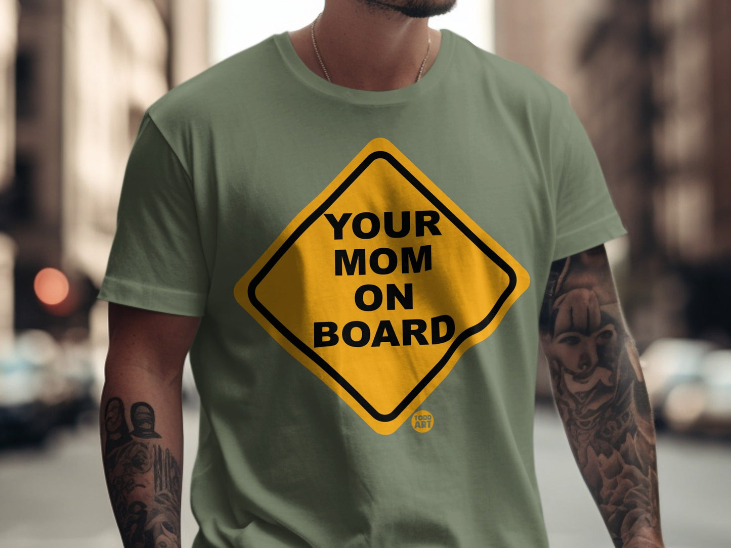 Yellow diamond sign on olive green t-shirt reads "Your Mom On Board" and "TOGO ART".