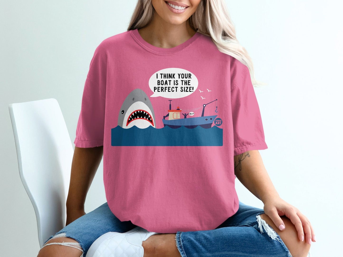 Pink t-shirt with cartoon shark and sinking boat graphic.
