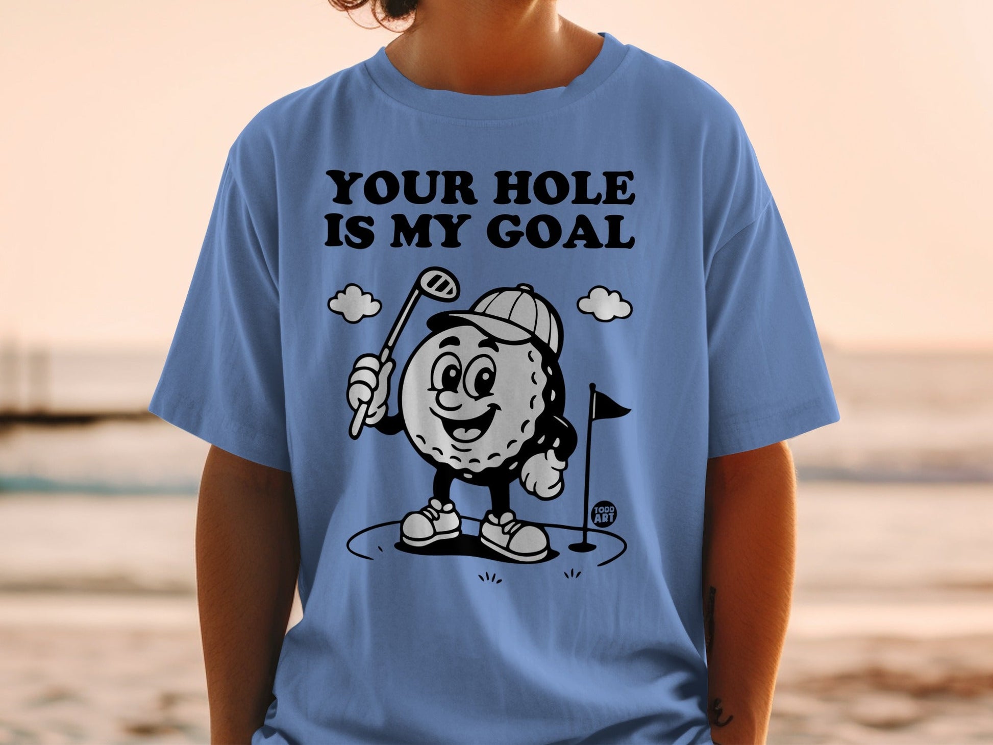Blue t-shirt with cartoon golf ball character and "YOUR HOLE IS MY GOAL" text.