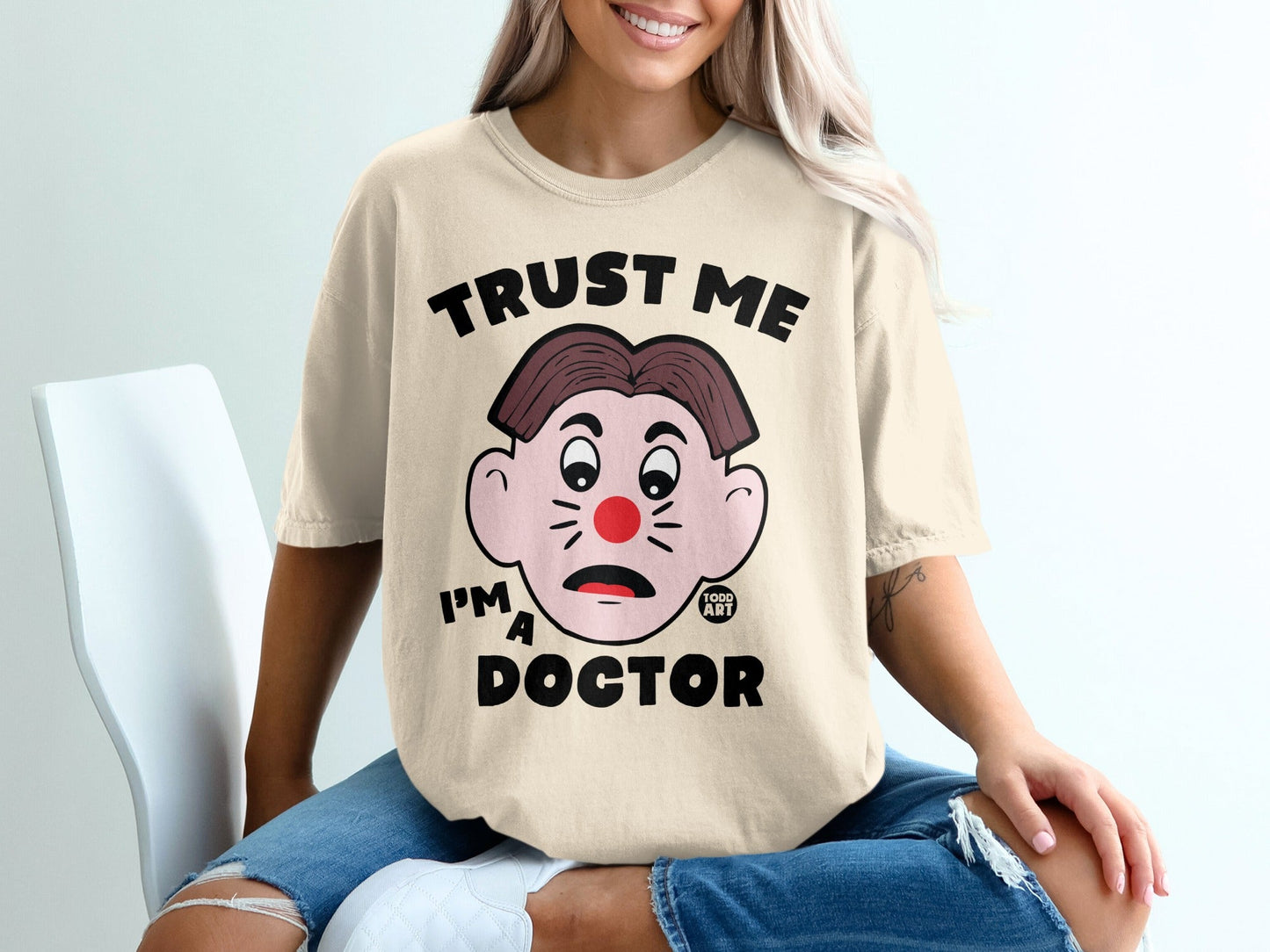 Cream t-shirt with "Trust Me I'm A Doctor" and a cartoon clown face.