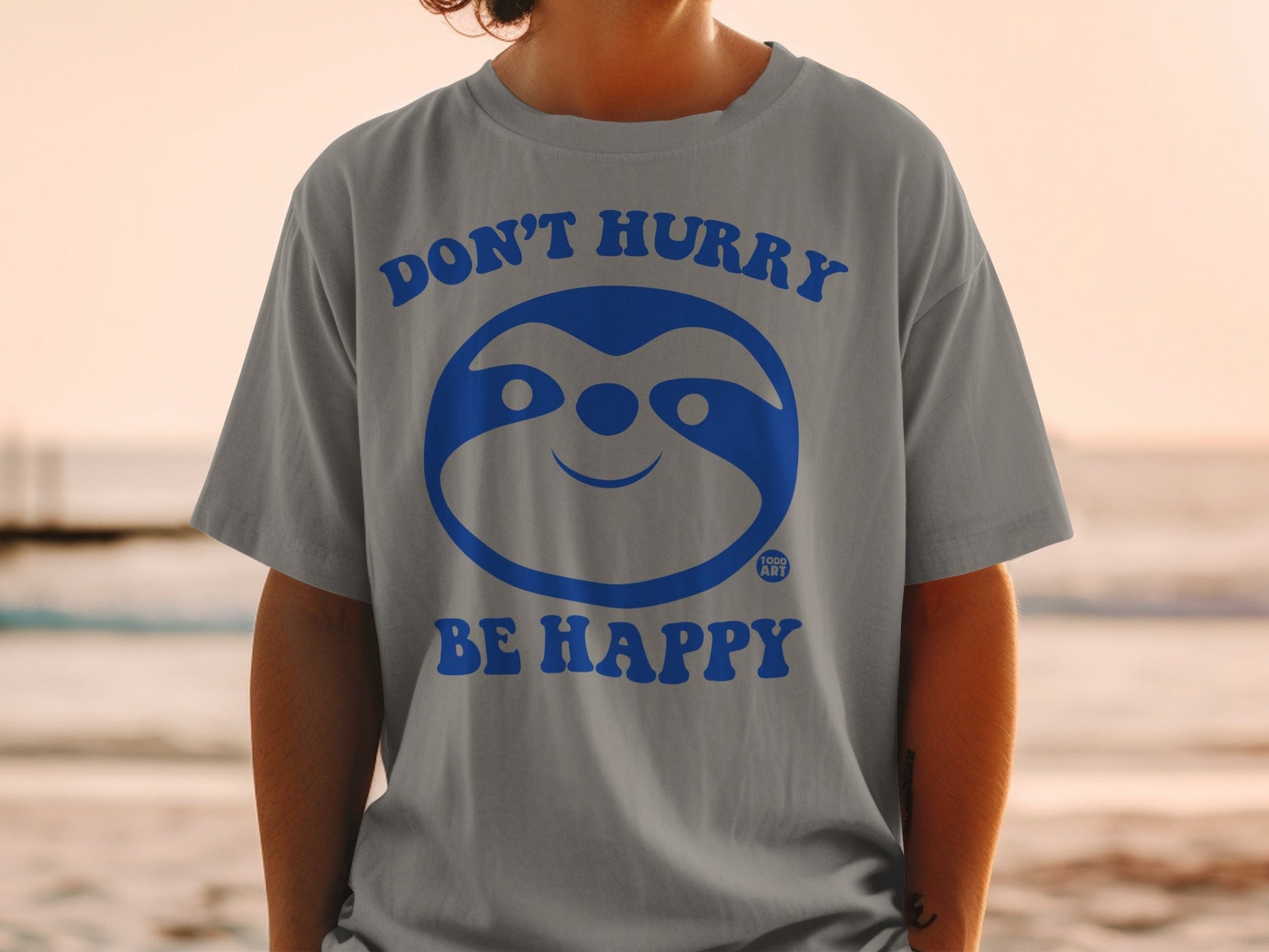 Gray t-shirt with blue sloth graphic and text "DON'T HURRY BE HAPPY".