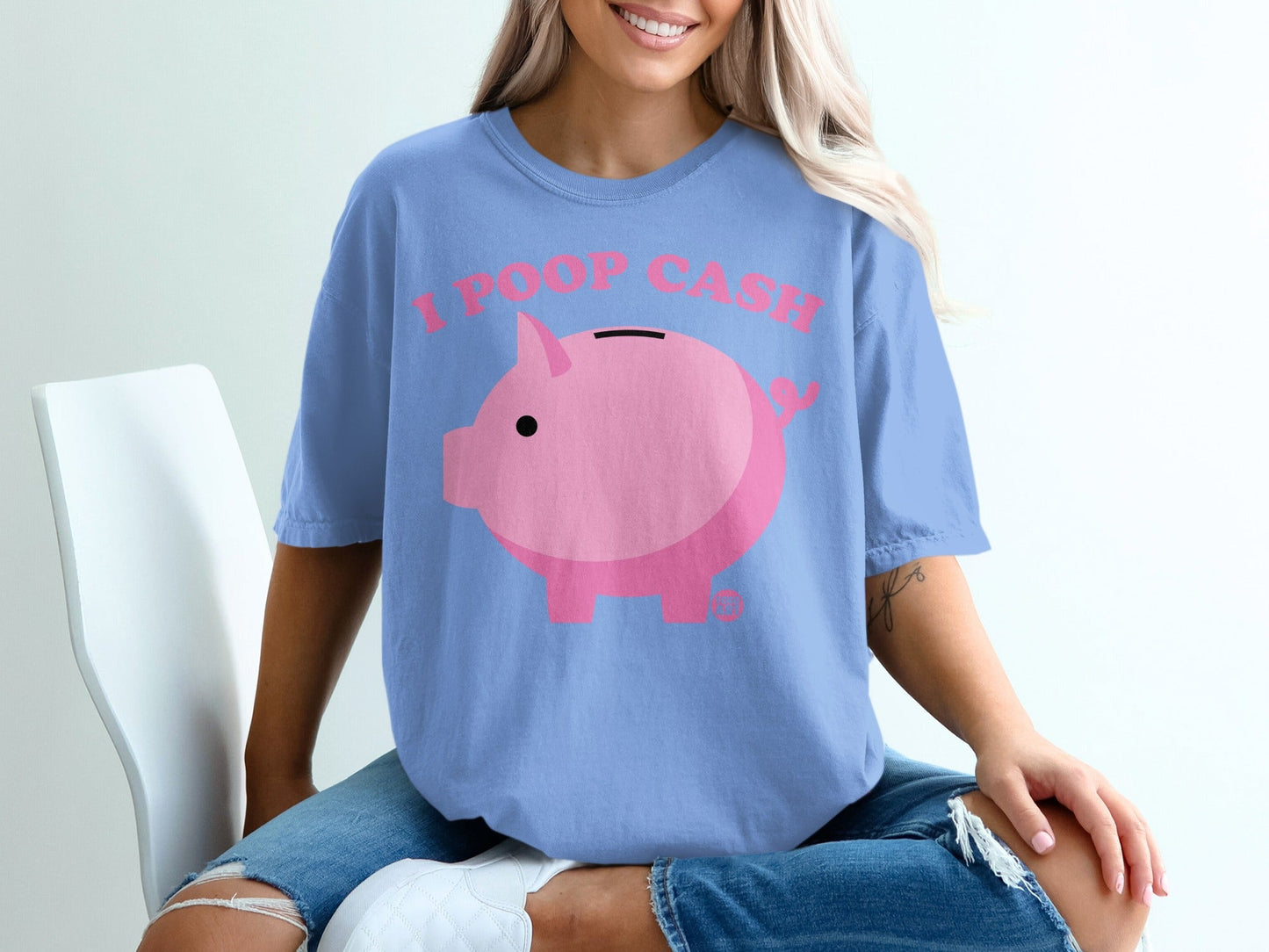 Pink piggy bank graphic with "I POOP CASH" text on a light blue t-shirt.