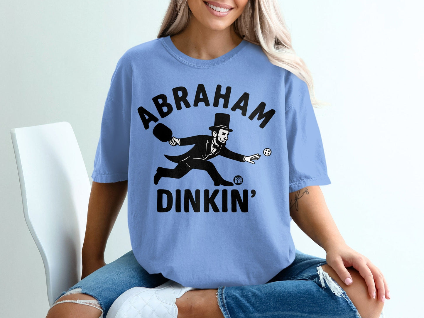Abraham dinkin' graphic on a light blue t-shirt.