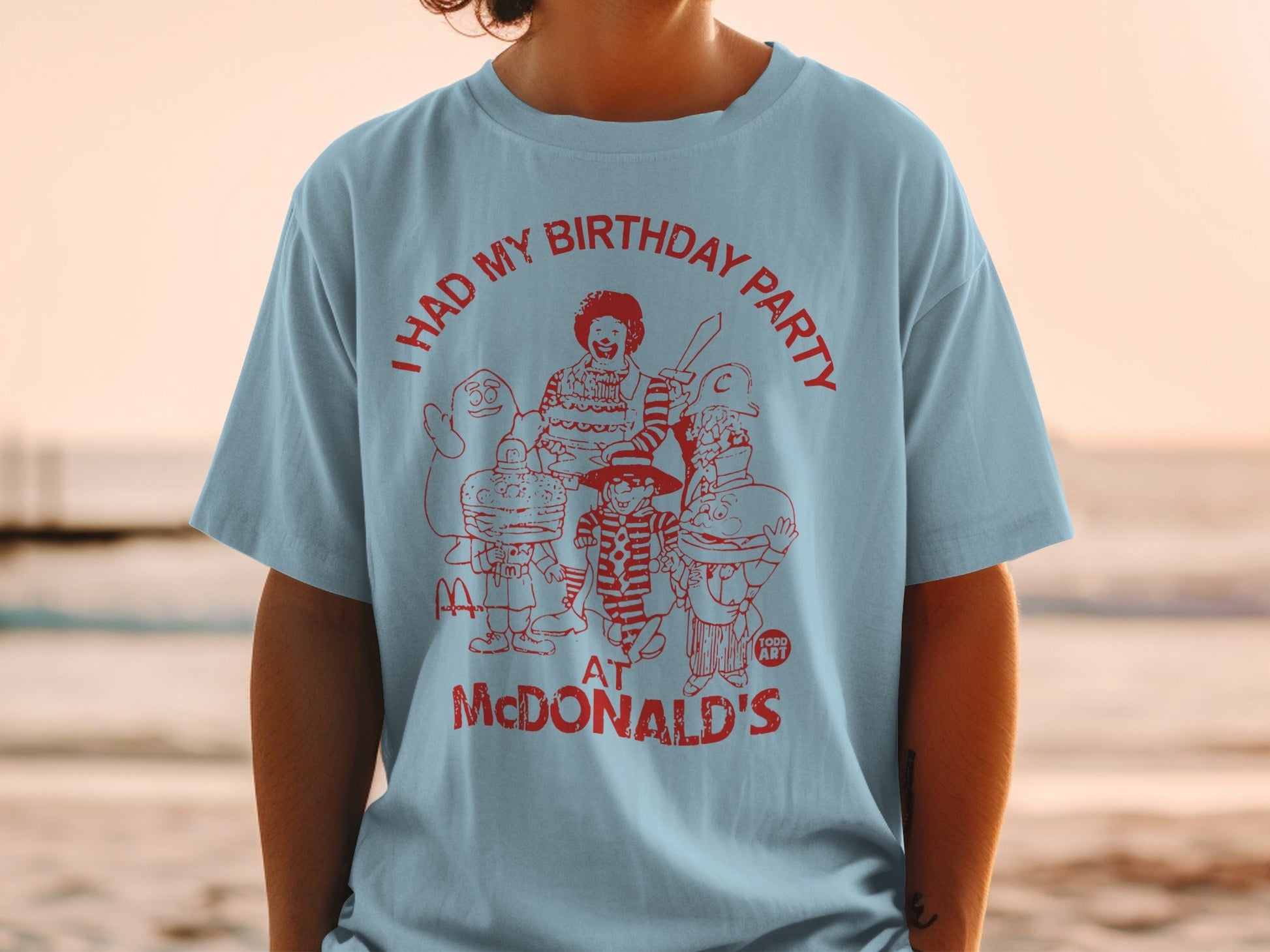Light blue t-shirt with red graphic of McDonald's characters celebrating a birthday.