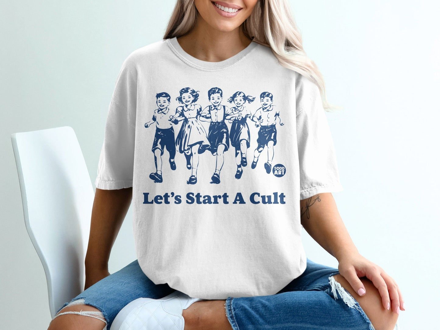 White t-shirt with blue graphic of children running and "Let's Start A Cult" text.
