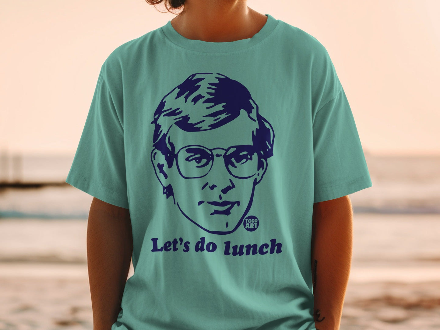 Teal t-shirt with graphic of person in glasses and "Let's do lunch" text.