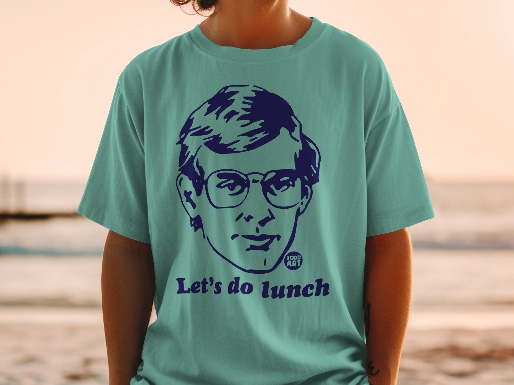 Teal t-shirt with graphic of person in glasses and "Let's do lunch" text.