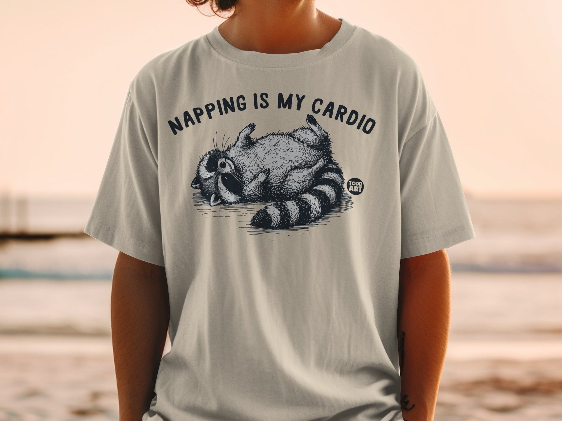 T-shirt with raccoon sleeping and text "Napping is my cardio".