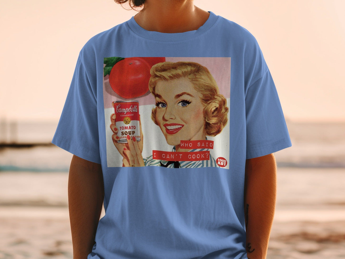 T-shirt featuring vintage Campbell's Tomato Soup advertisement with text "WHO SAID I CAN'T COOK?".