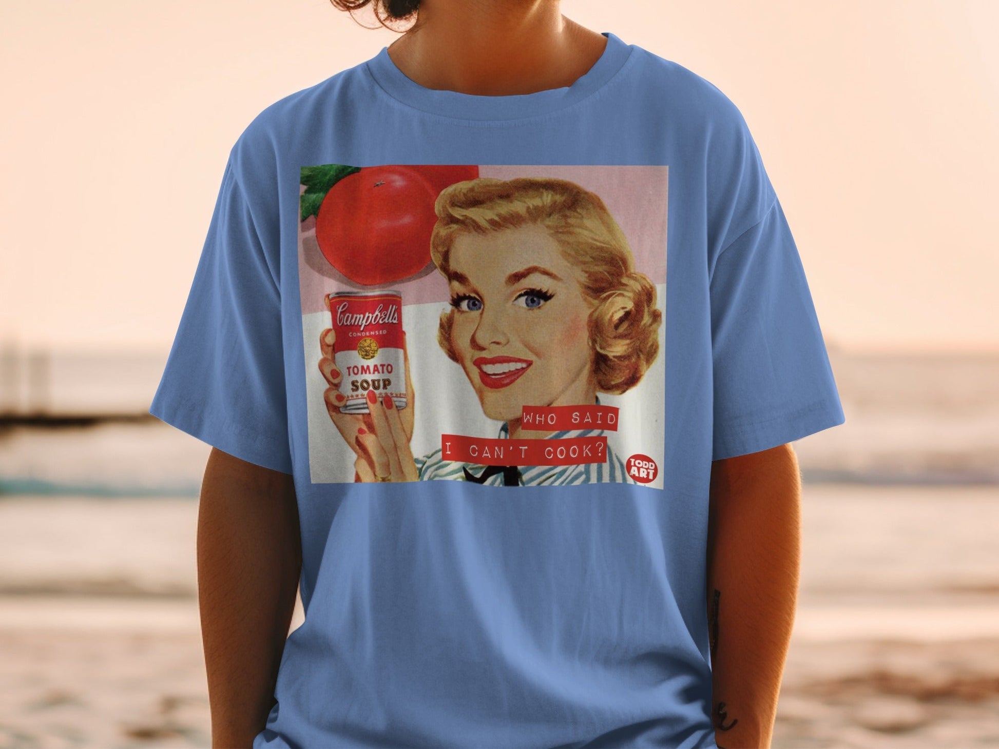 T-shirt featuring vintage Campbell's Tomato Soup advertisement with text "WHO SAID I CAN'T COOK?".