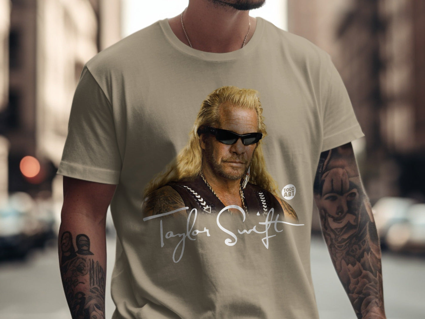 Dog the Bounty Hunter wearing a tan t-shirt with a signature and "TODD ART".