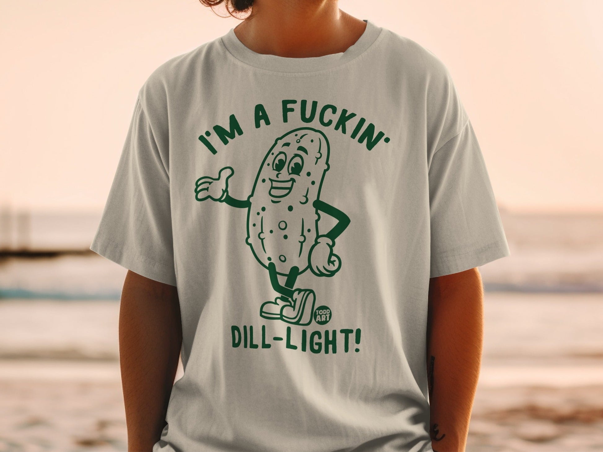 Green t-shirt with cartoon pickle graphic saying "I'm a fuckin' dill-light!"