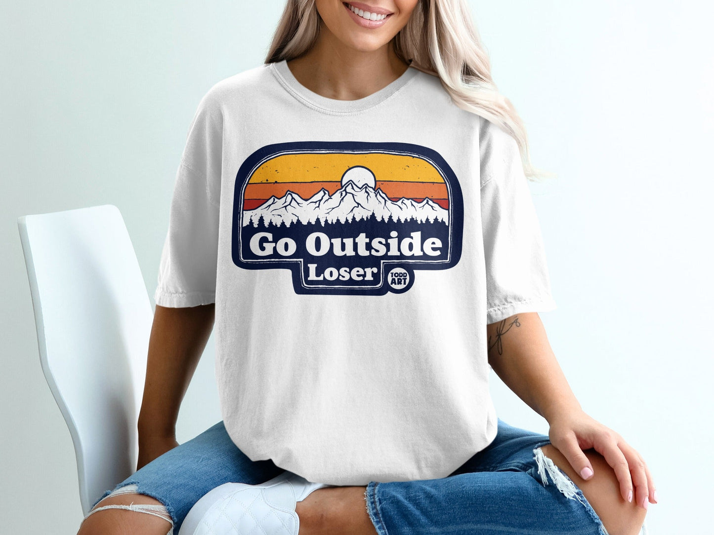 T-shirt graphic with mountains, sun, and text "Go Outside Loser".
