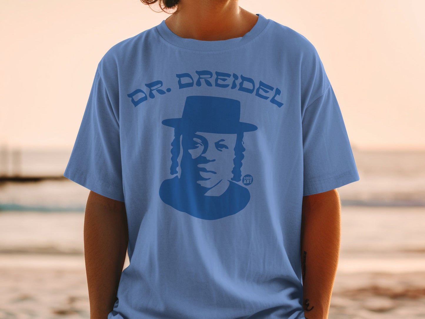 Blue t-shirt with a silhouetted man wearing a hat and the text "DR. DREIDEL"
