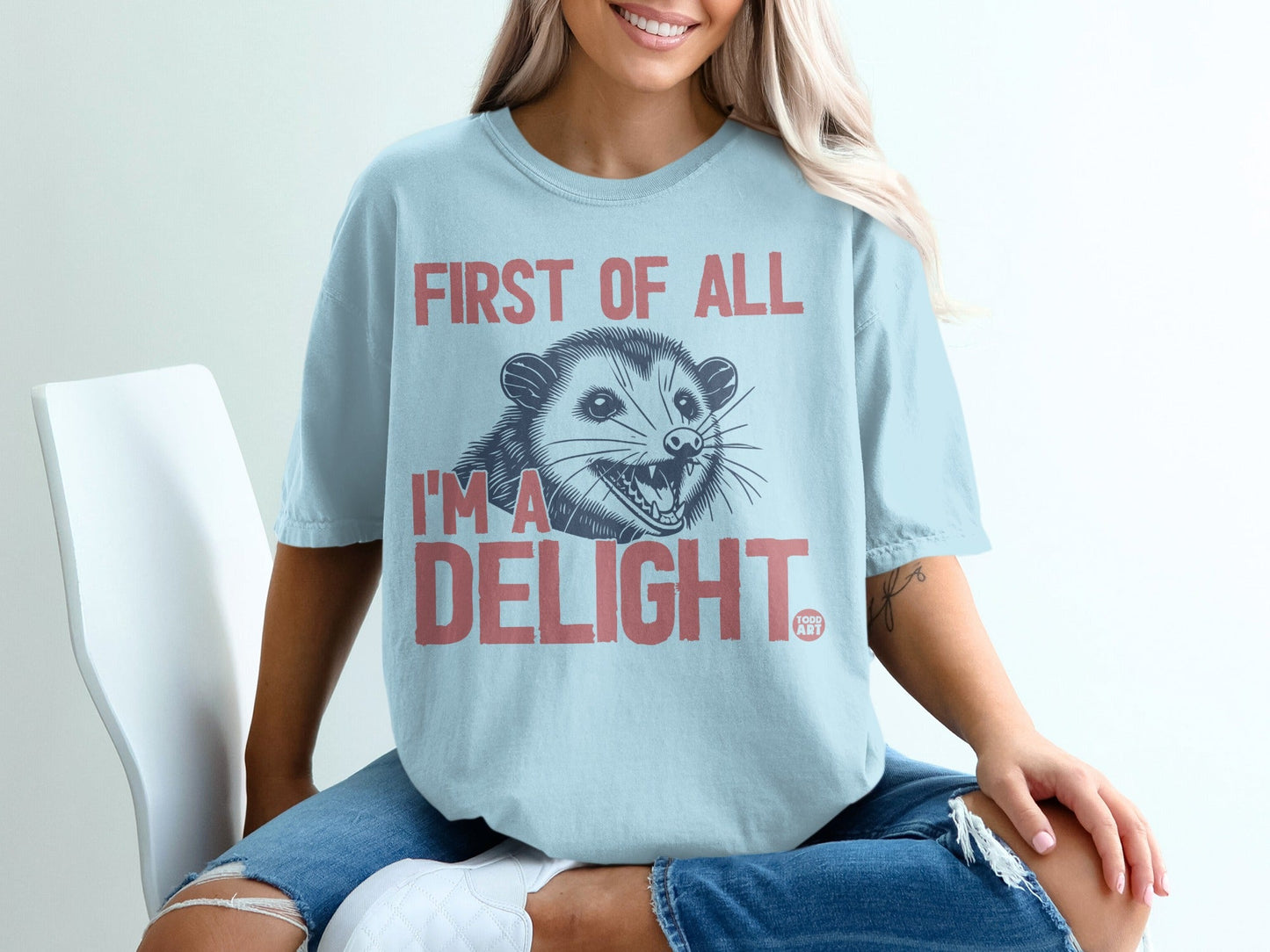 Light blue t-shirt with a possum and "First of all I'm a delight" text.