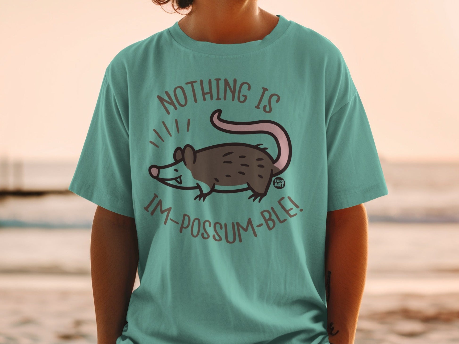Teal t-shirt with possum cartoon and "Nothing is im-possum-ble!" text.