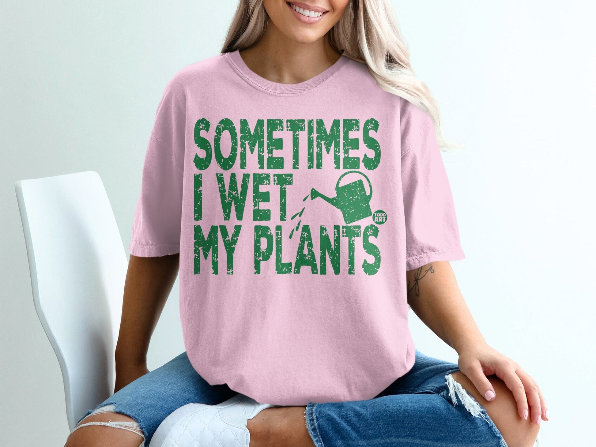 Pink t-shirt with green text "SOMETIMES I WET MY PLANTS" and watering can graphic.
