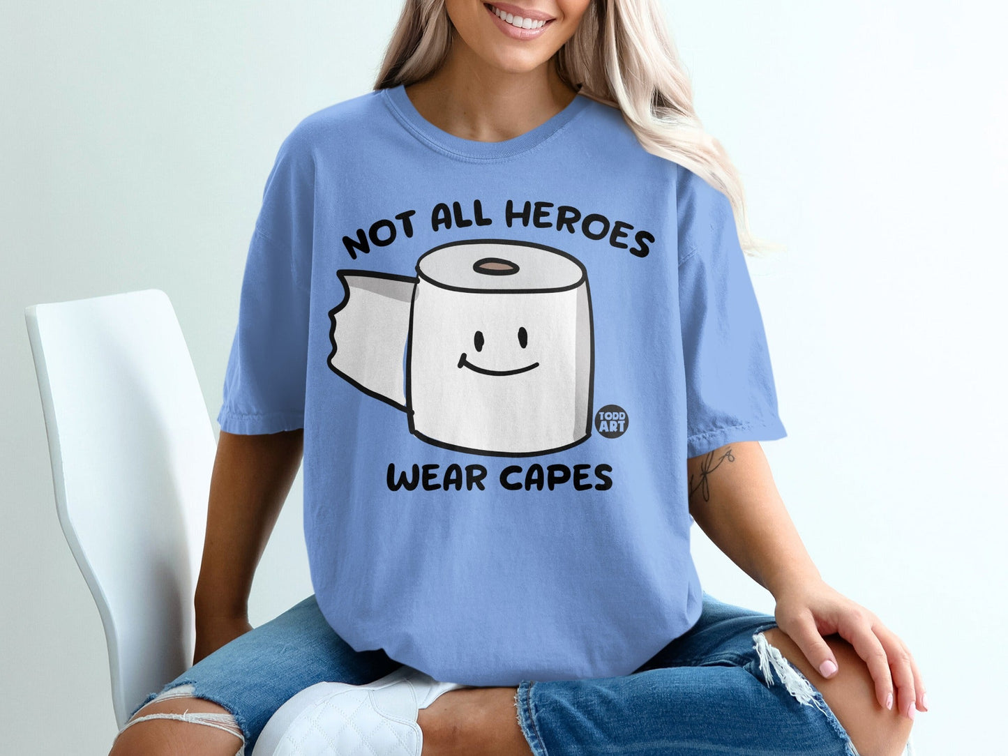 Blue t-shirt with a cartoon toilet paper roll and text "NOT ALL HEROES WEAR CAPES".