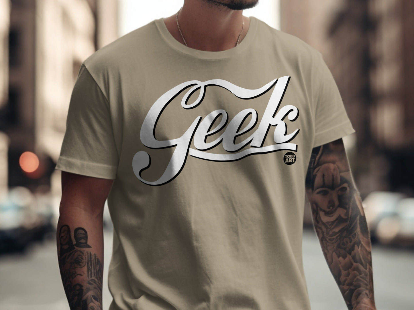 Tan t-shirt with "Geek Food Art" text and tattooed arms.