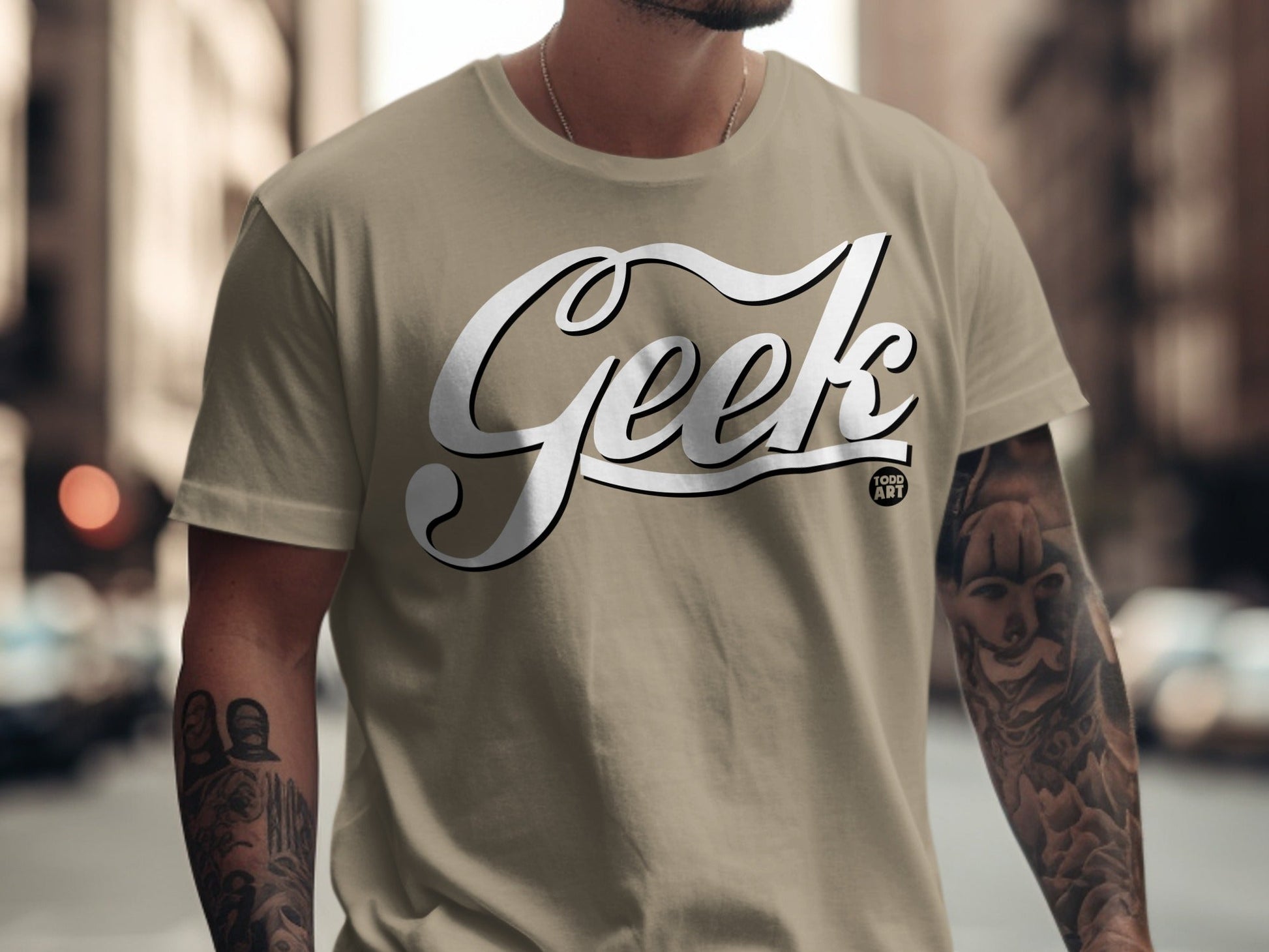 Tan t-shirt with "Geek Food Art" text and tattooed arms.