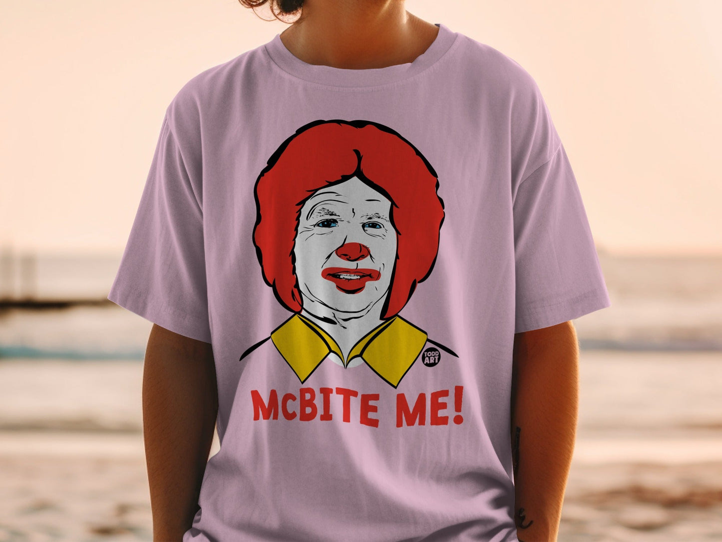Pink t-shirt with a graphic of Ronald McDonald and the text "MCBITE ME!".