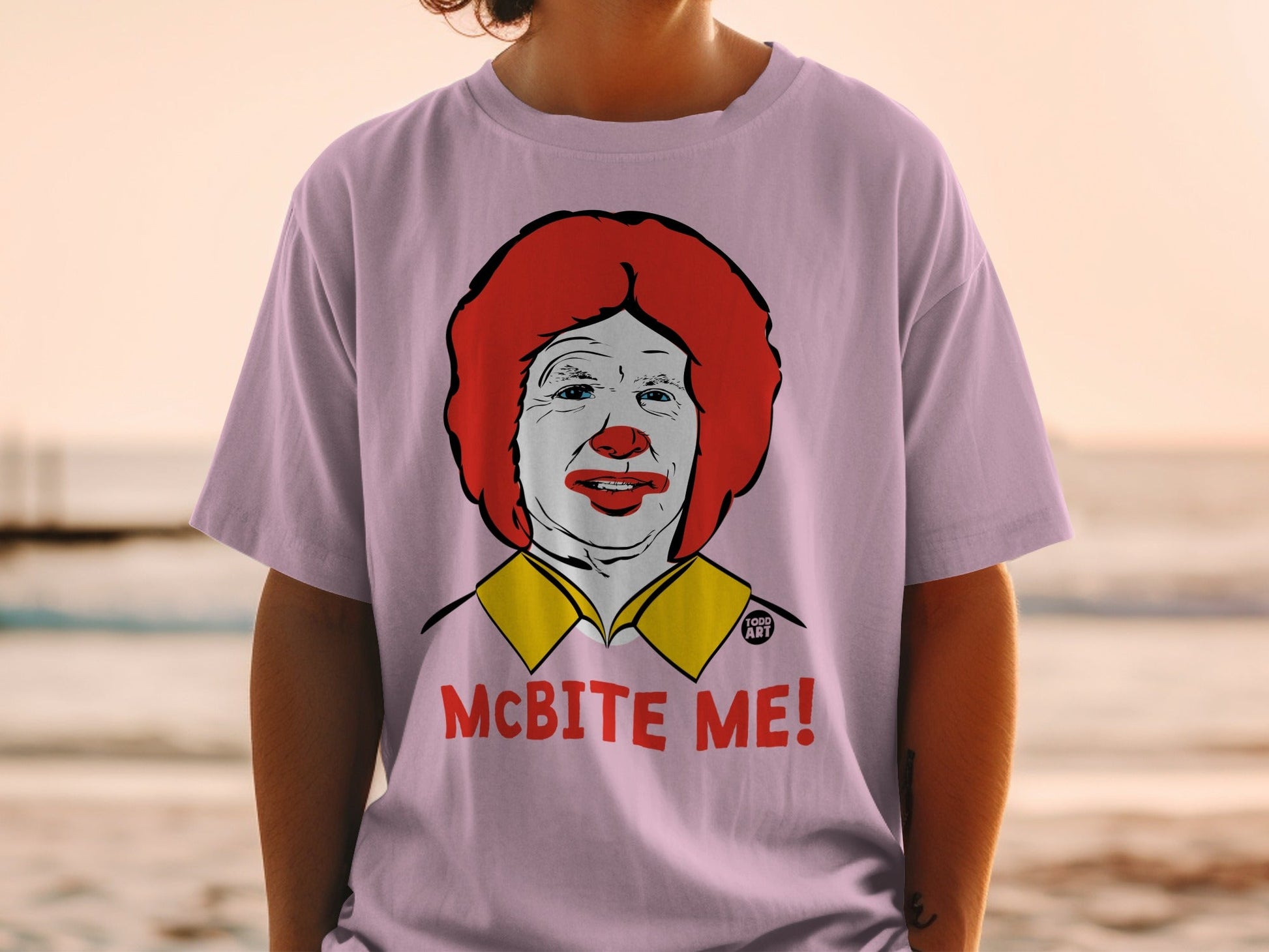 Pink t-shirt with a graphic of Ronald McDonald and the text "MCBITE ME!".