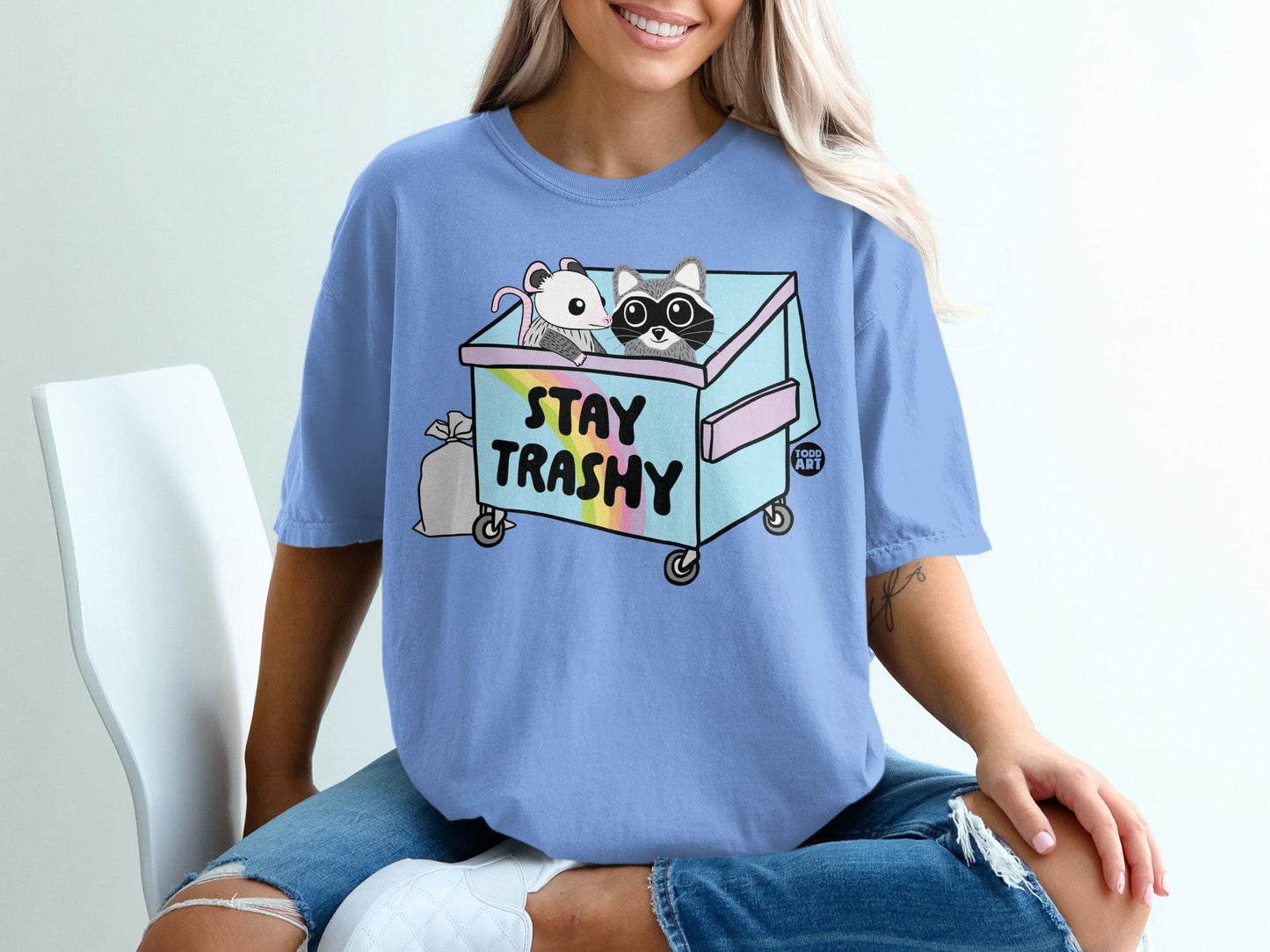 Light blue t-shirt with trash can and raccoon design.