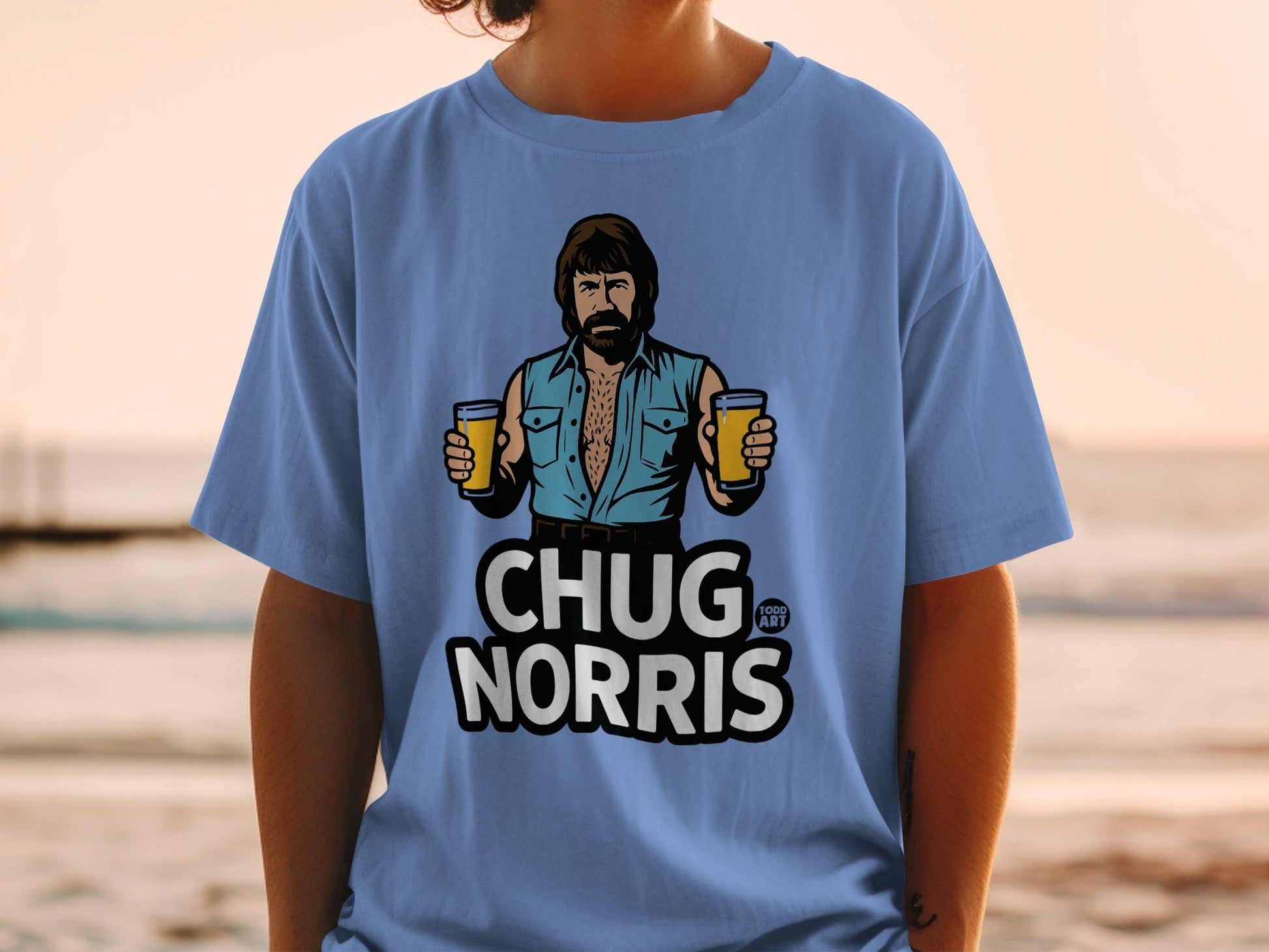 Chuck Norris graphic on a light blue t-shirt holding two glasses of beer.