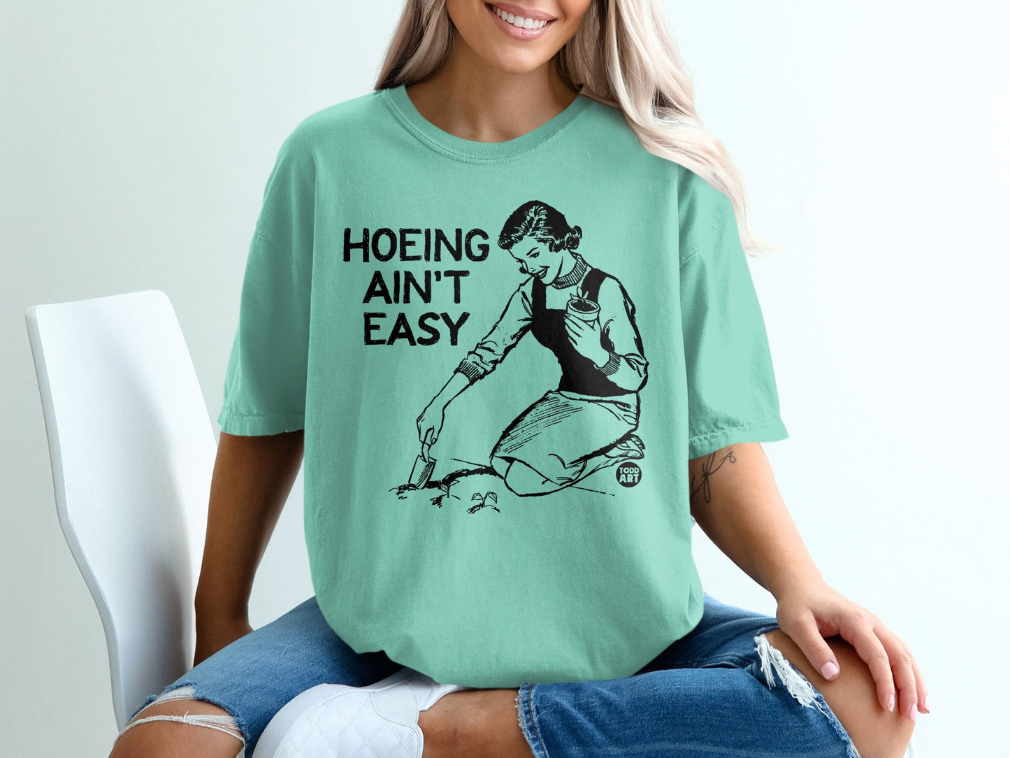 Woman in t-shirt with text "Hoeing Ain't Easy" gardening.