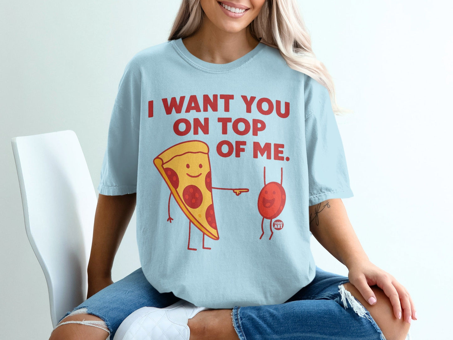 Light blue t-shirt with pizza slice saying "I want you on top of me".