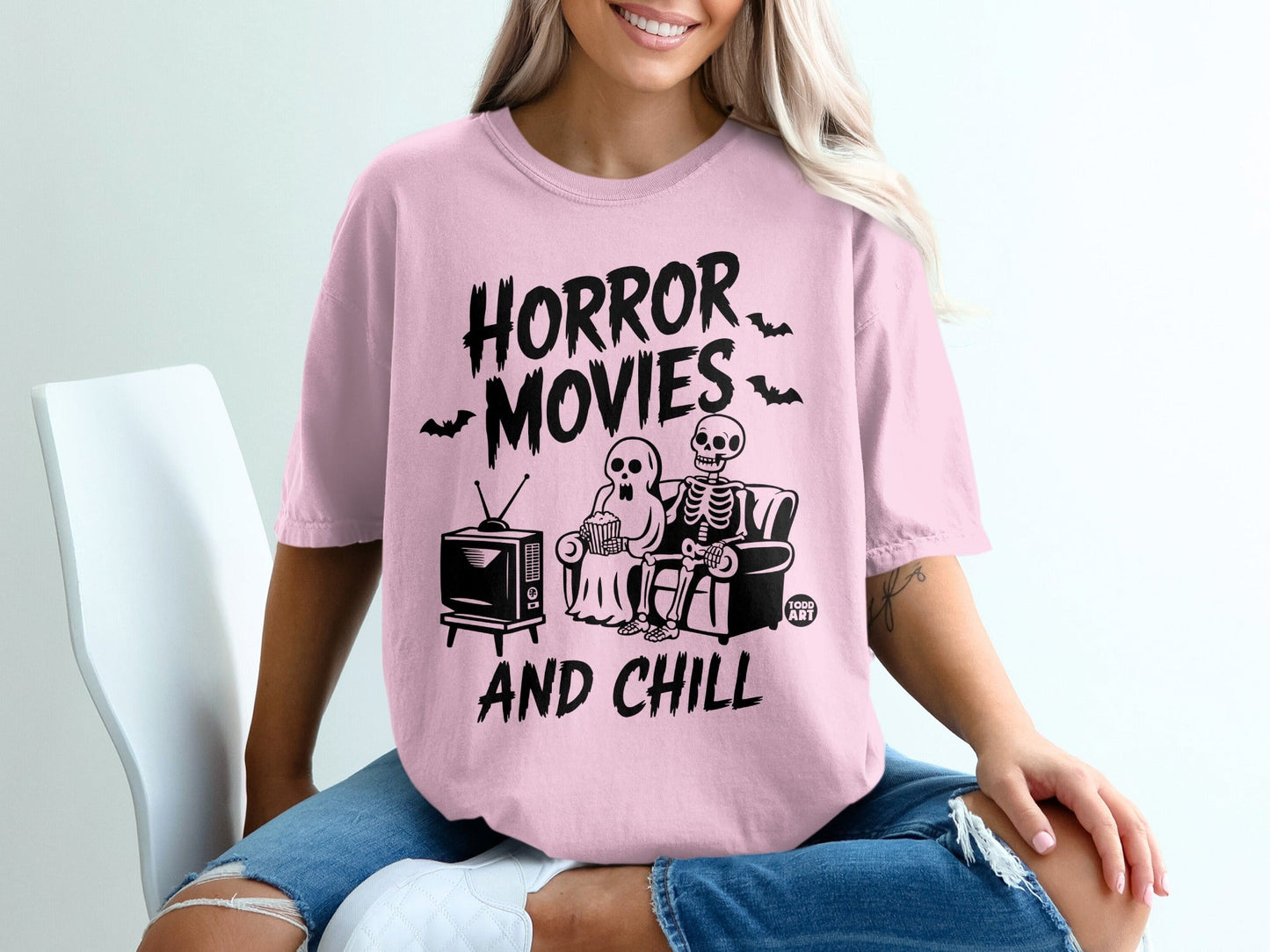 Pink t-shirt with "Horror Movies And Chill" text, skeletons watching TV.