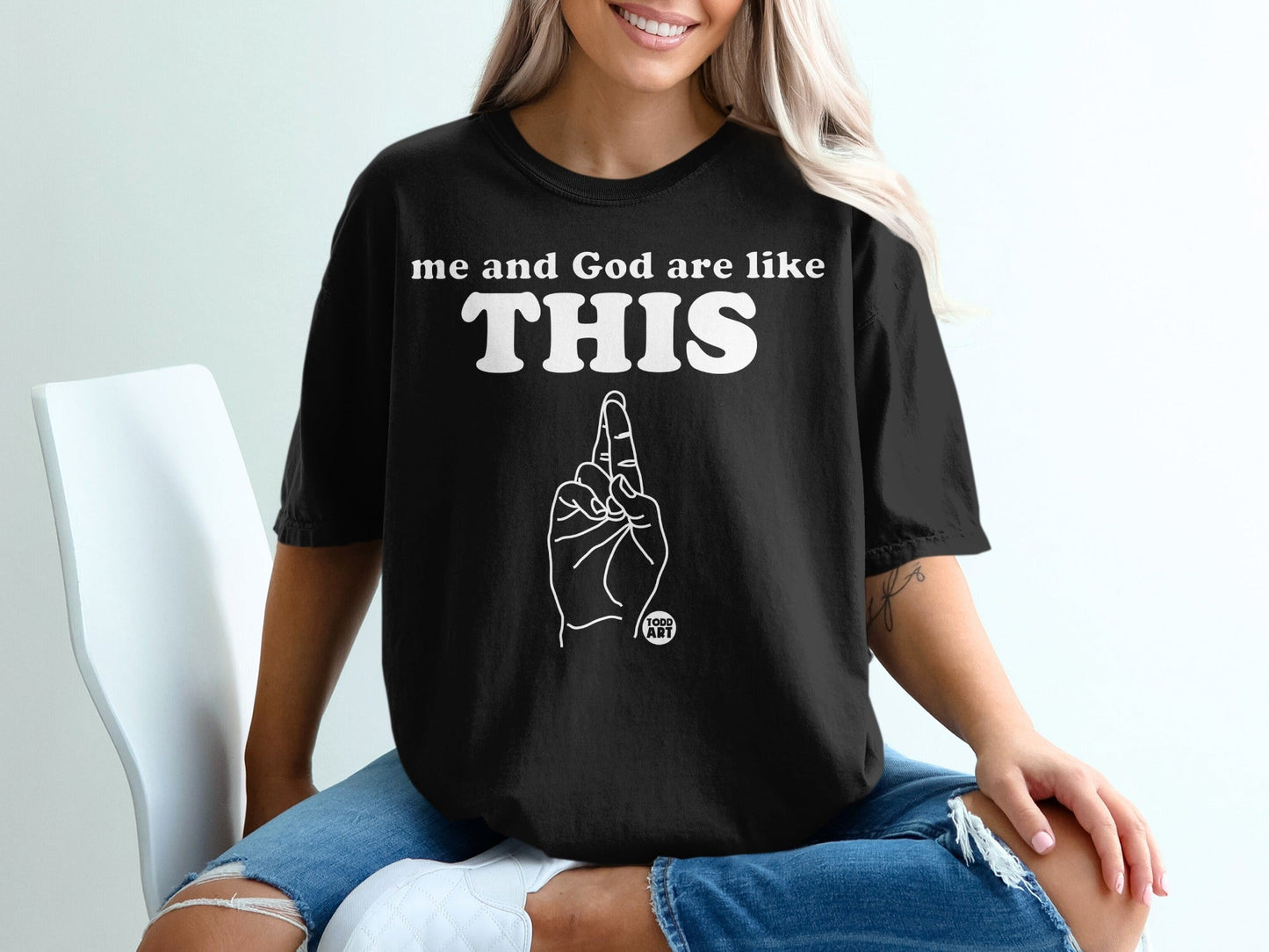 Black t-shirt with white text "me and God are like THIS" and a graphic of a hand pointing up.