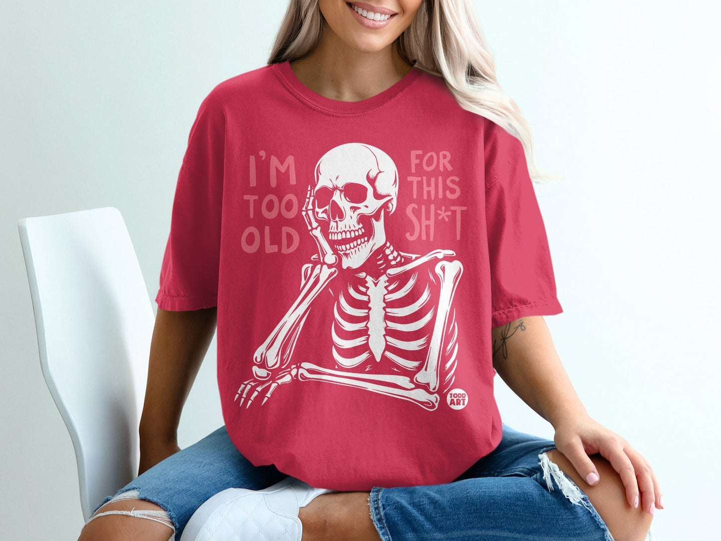 Woman wearing red t-shirt with skeleton and "I'm too old for this sh*t" text.