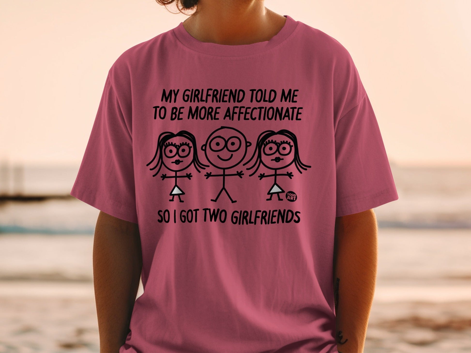 Pink t-shirt with cartoon figures and text "SO I GOT TWO GIRLFRIENDS".