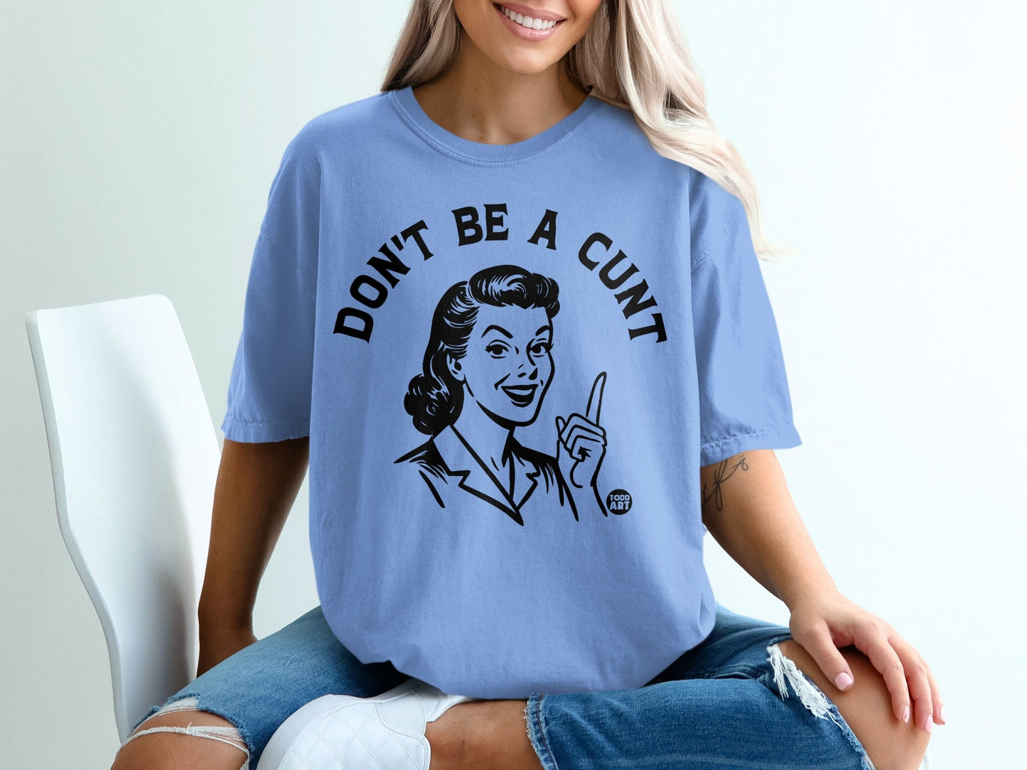 Light blue t-shirt with "DON'T BE A CUNT" text and retro woman illustration.