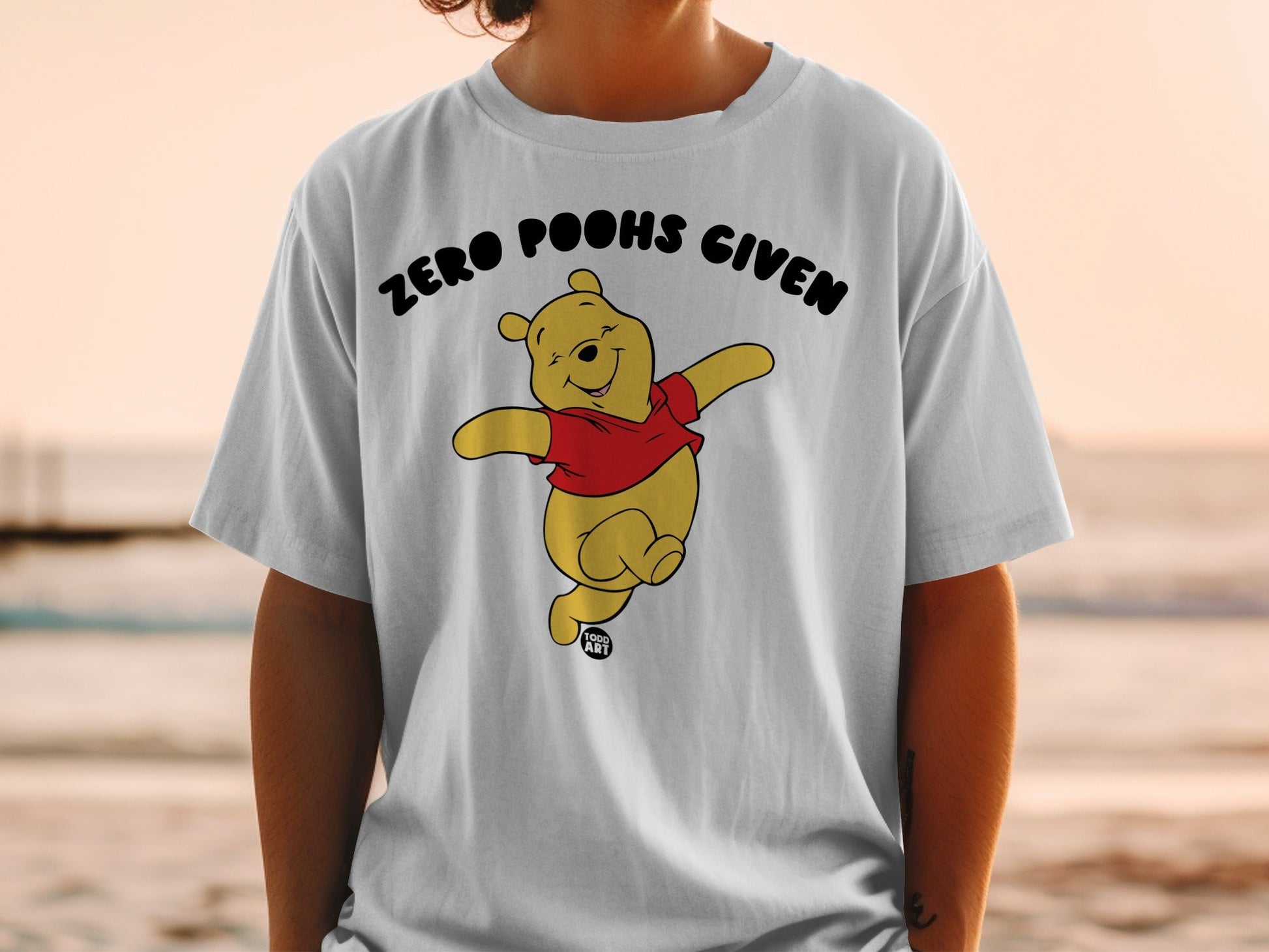 Winnie the Pooh graphic tee with text "ZERO POOHS GIVEN" and artist's signature.