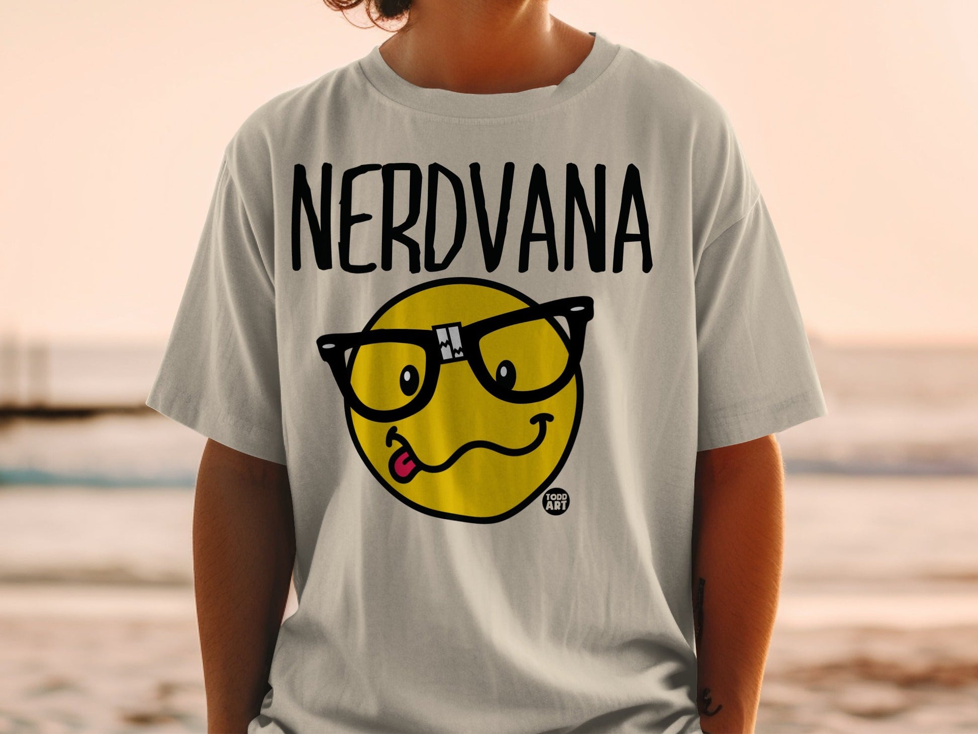 NERDVANA t-shirt with a yellow smiley face wearing glasses and sticking out its tongue.