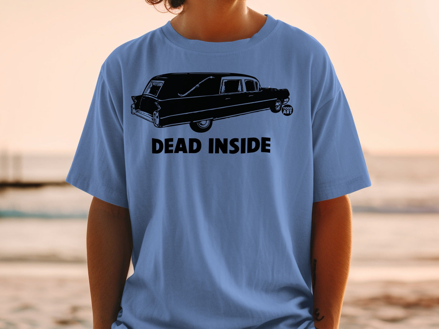 Black hearse graphic with "DEAD INSIDE" text on a blue t-shirt.