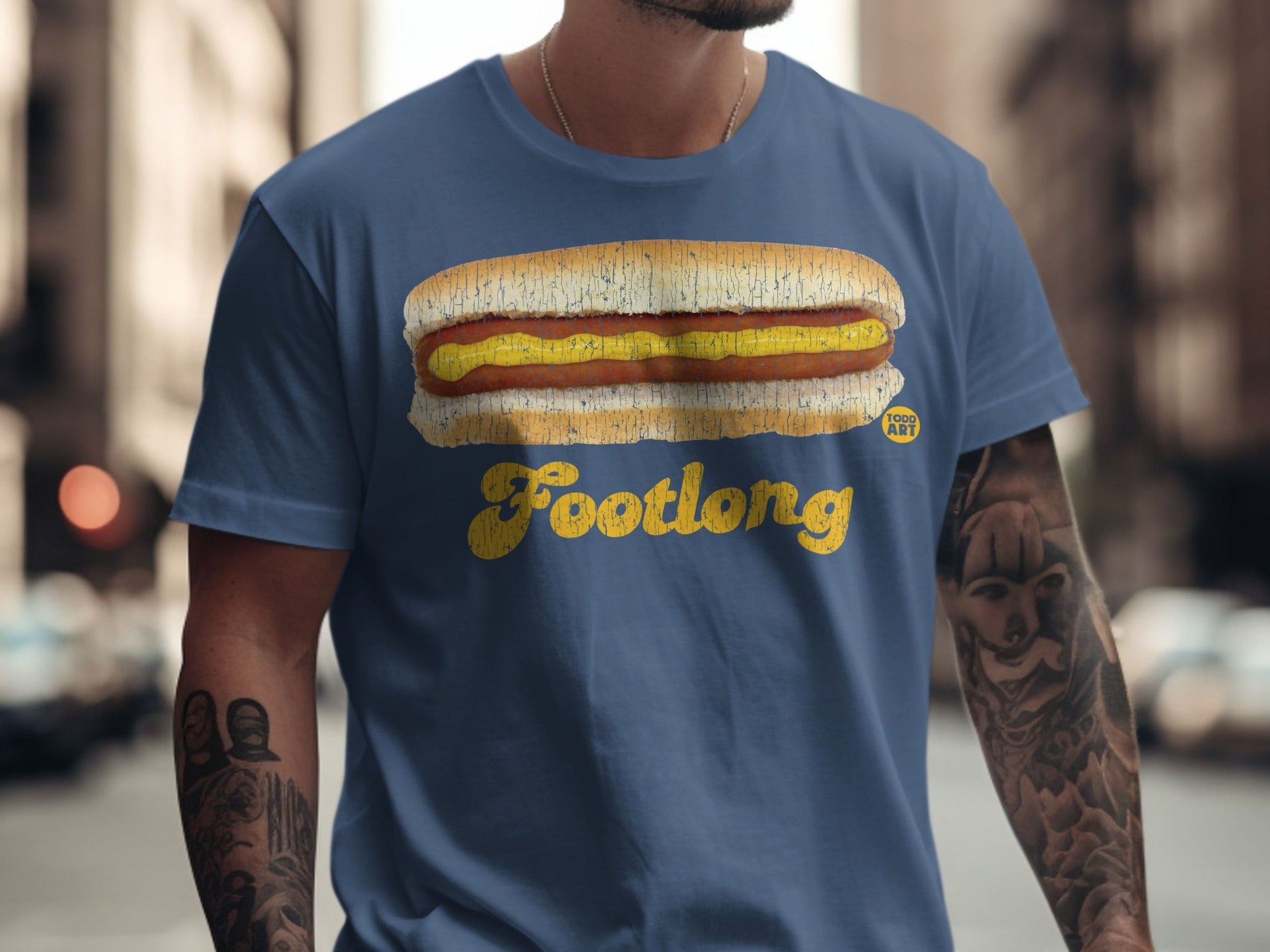 Blue t-shirt with a graphic of a footlong hot dog with mustard and "Footlong" text.
