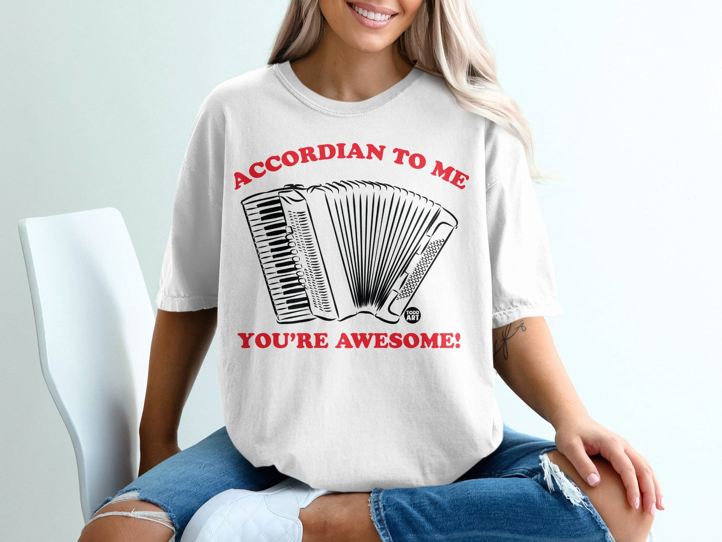 White t-shirt with "ACCORDION TO ME YOU'RE AWESOME!" and accordion graphic.