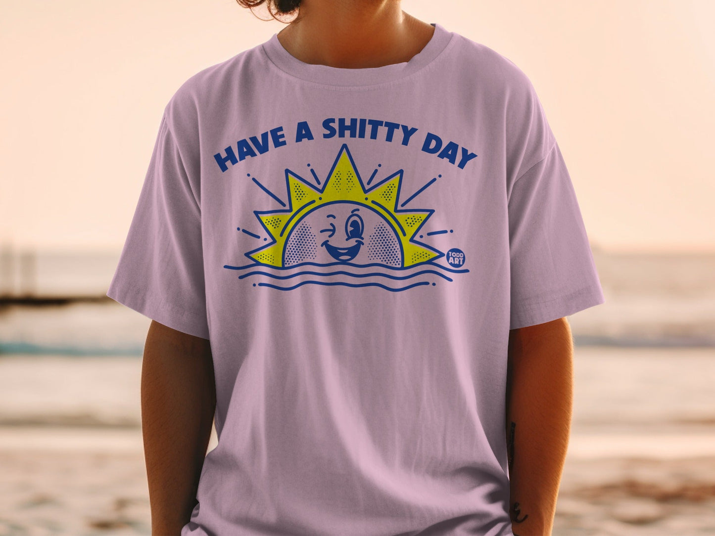 Purple t-shirt with a cartoon sun and text "HAVE A SHITTY DAY".