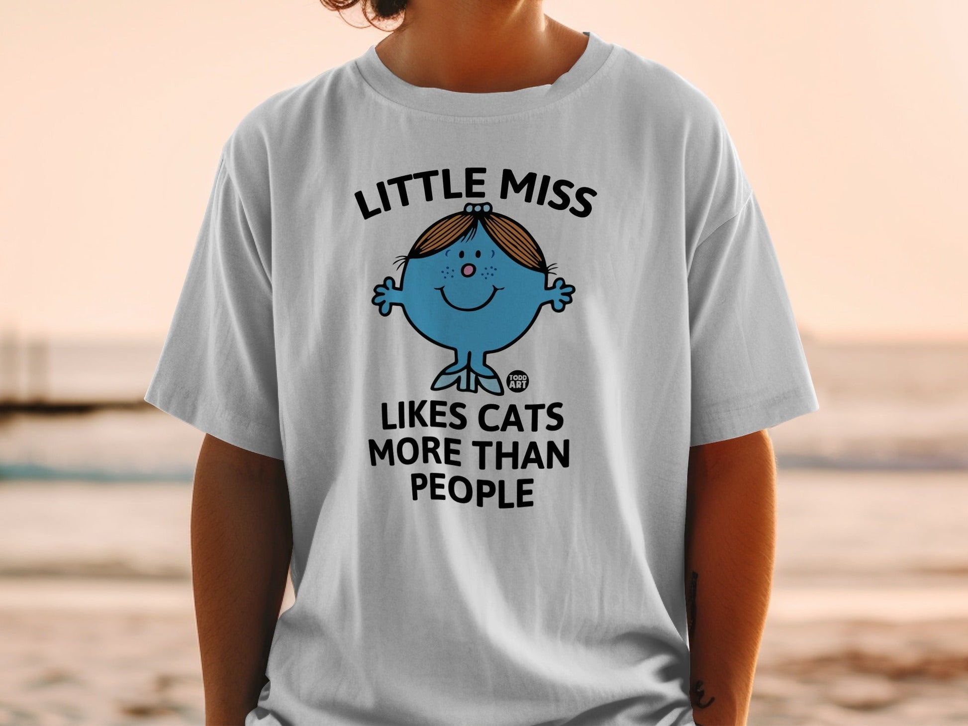 White t-shirt with "Little Miss Likes Cats More Than People" text and cartoon character.