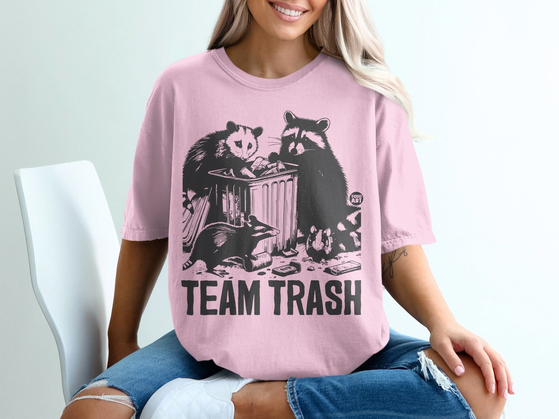 T-shirt with raccoon, possum, and skunk in trash can graphic and "Team Trash" text.