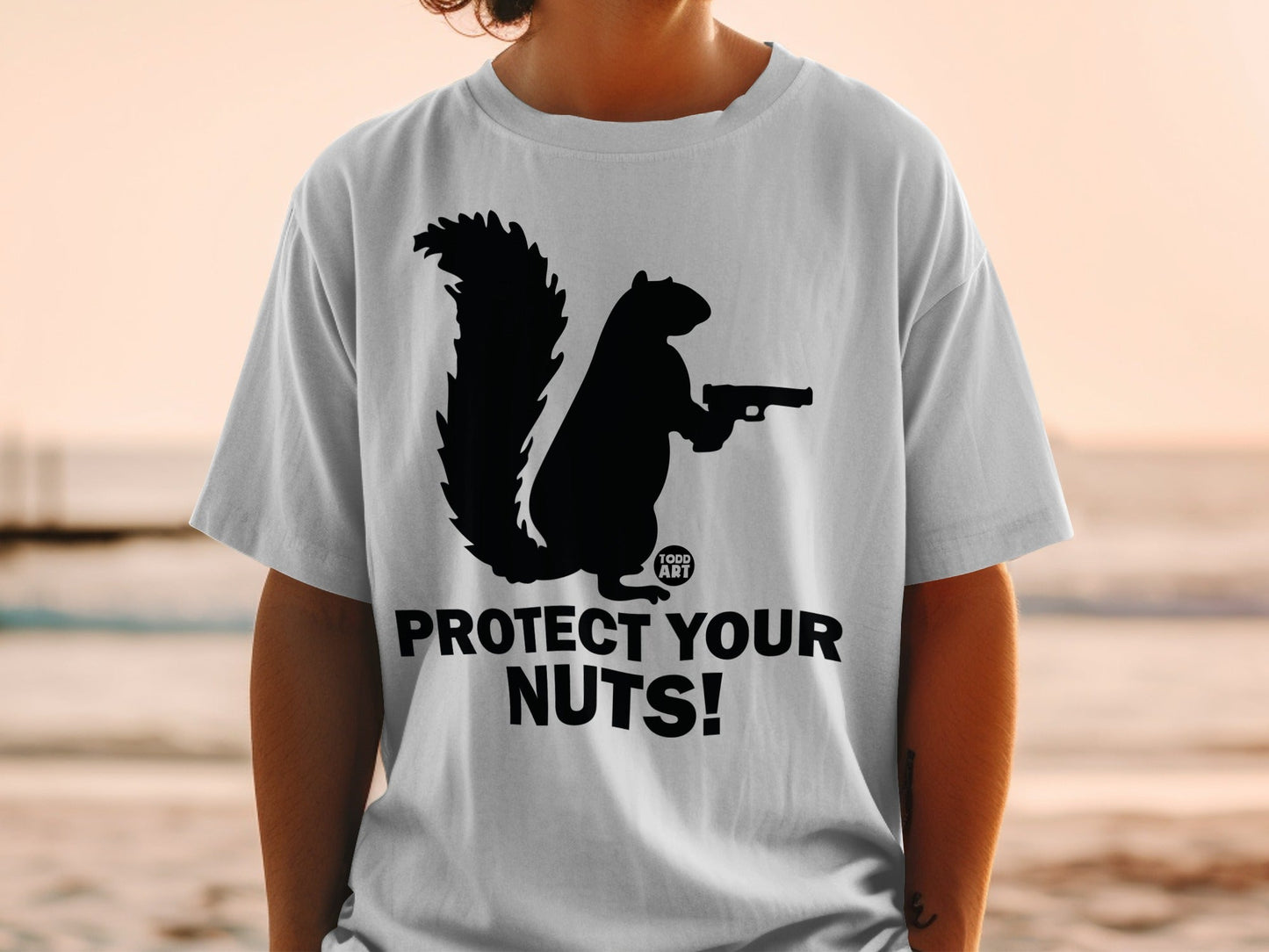 Black squirrel silhouette holding a gun on a white t-shirt, "Protect Your Nuts!"