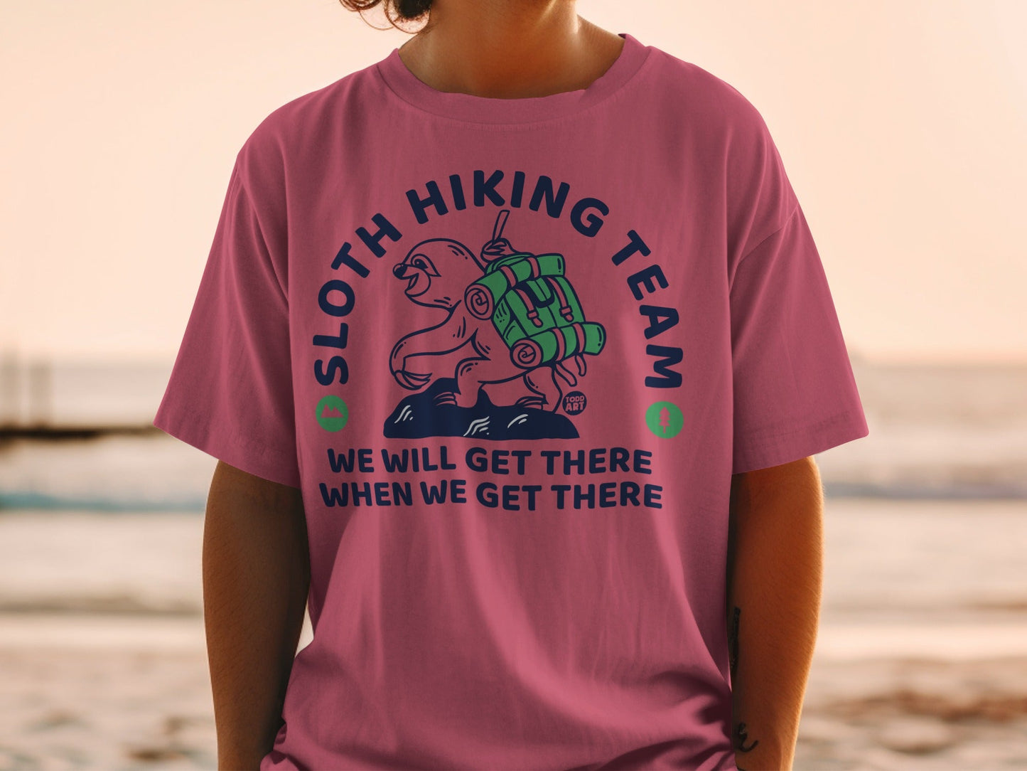 Sloth wearing a backpack, "Sloth Hiking Team" text, on a pink t-shirt.