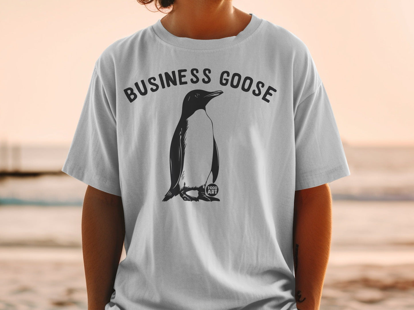 White t-shirt with a black penguin illustration and "BUSINESS GOOSE" text.