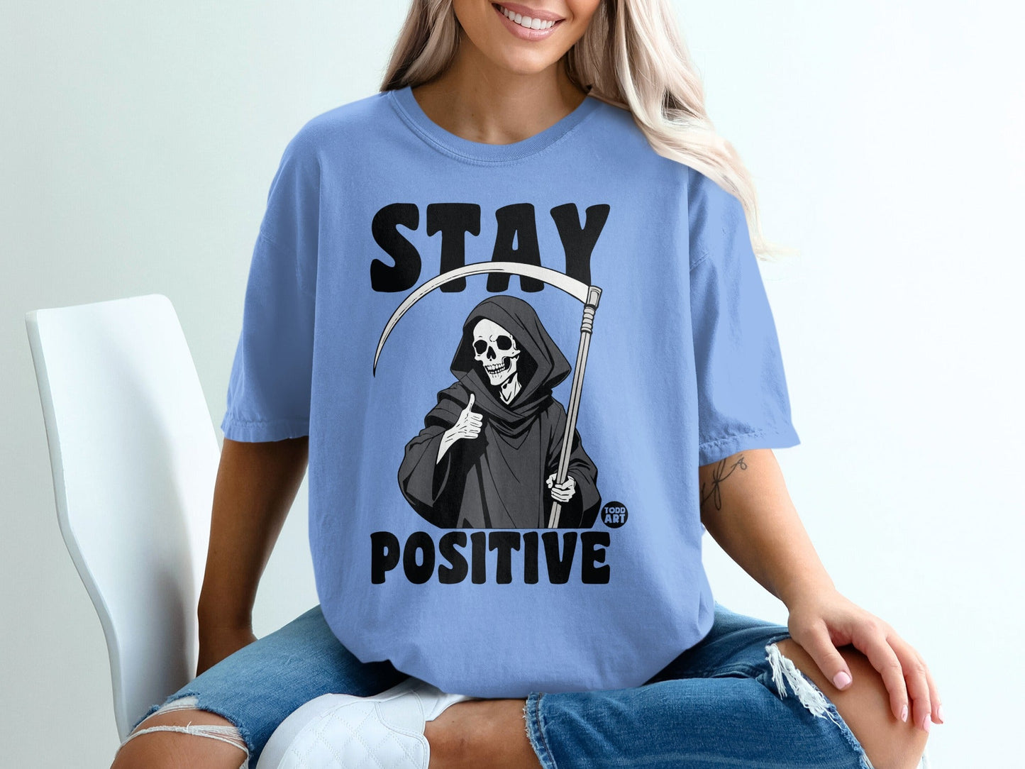 Blue t-shirt with "STAY POSITIVE" and grim reaper giving a thumbs up.