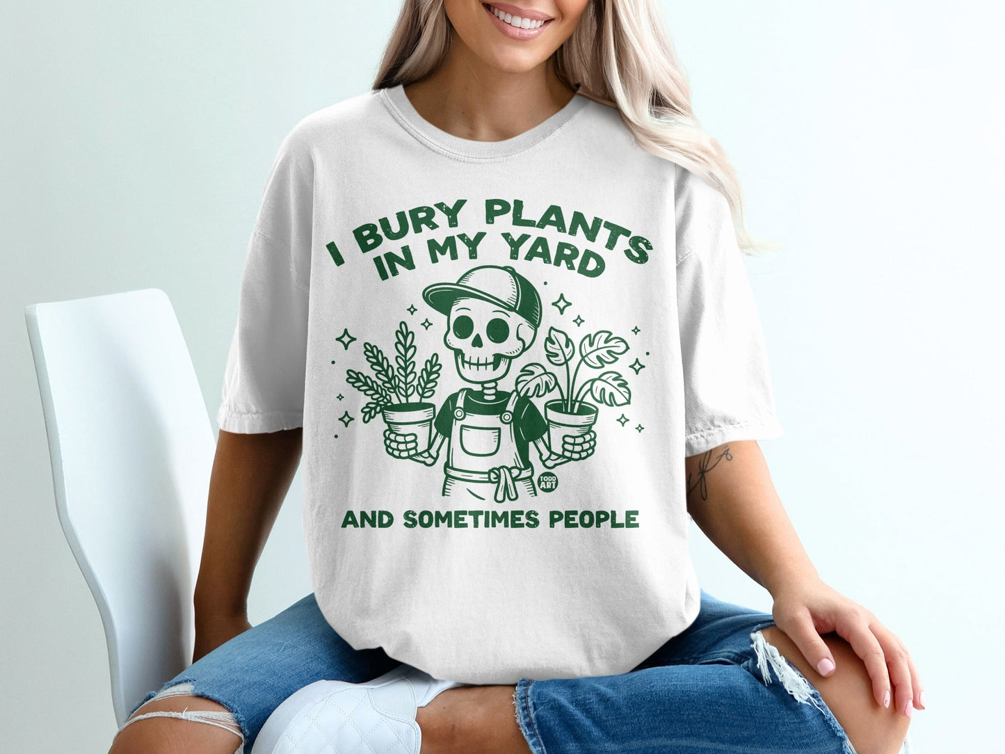White t-shirt with green text and skeleton graphic holding potted plants.